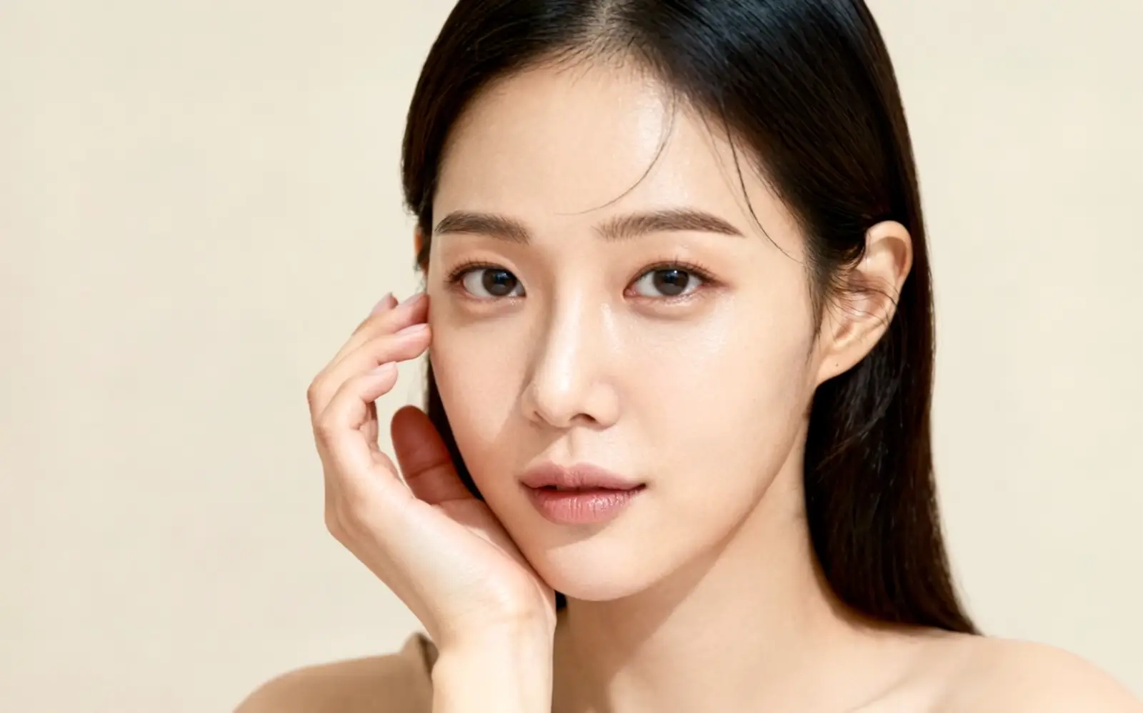 턱에 손을 대고 정면을 보는 맑은 피부의 여성